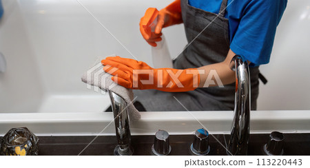 Professional cleaning service company employee in rubber gloves cleaning and detergent spray in bathroom 113220443