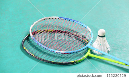White badminton shuttlecocks and badminton rackets on green floor indoor badminton court soft and selective focus on shuttlecocks and the rackets 113220529