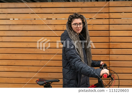 Lifestyle concept, a young pretty European woman with pigtails dressed in a warm winter jacket rides 113220603