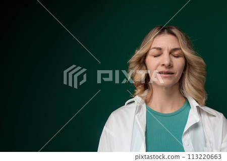 Woman Standing With Eyes Closed in Front of Green Background 113220663