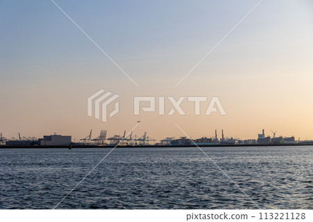 Ships float across the North Sea. Windmills in the background. Sea port in the Netherlands. A lot of cranes for loading goods. Different ships and barges. Ships float across the North Sea. Windmills in the background. Sea port in the Netherlands. A lot of cranes for loading goods. Different ships and barges. 113221128