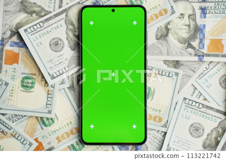 Smartphone with green screen on pile of dollar banknotes, top view. Concept of online earnings 113221742