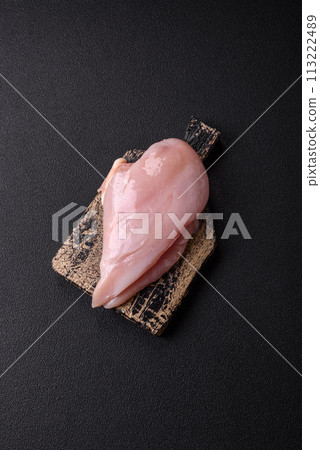 Fresh chicken fillet on a dark concrete table with spices and herbs Fresh chicken fillet on a dark concrete table with spices and herbs 113222489