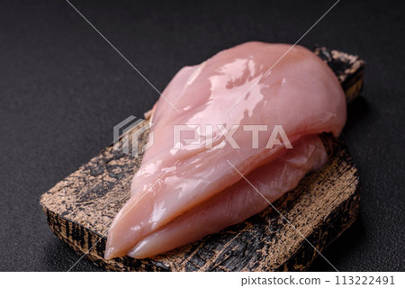 Fresh chicken fillet on a dark concrete table with spices and herbs Fresh chicken fillet on a dark concrete table with spices and herbs 113222491