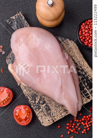 Fresh chicken fillet on a dark concrete table with spices and herbs Fresh chicken fillet on a dark concrete table with spices and herbs 113222499