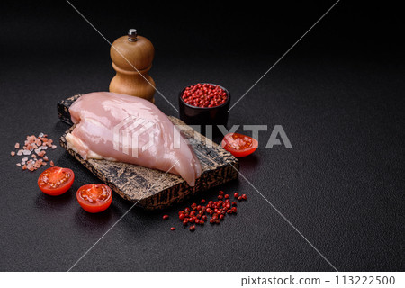 Fresh chicken fillet on a dark concrete table with spices and herbs Fresh chicken fillet on a dark concrete table with spices and herbs 113222500