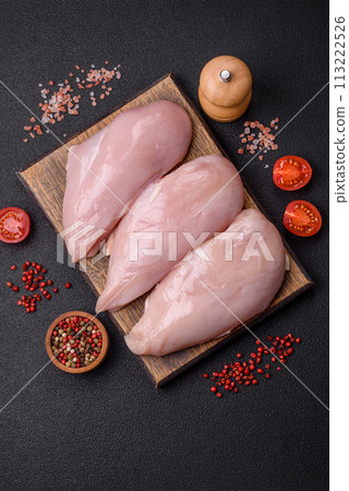 Fresh chicken fillet on a dark concrete table with spices and herbs Fresh chicken fillet on a dark concrete table with spices and herbs 113222526