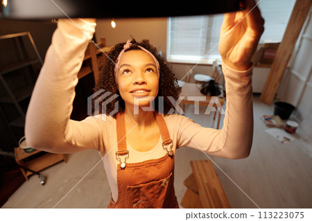 Young owner of cafe hanging new lamp 113223075