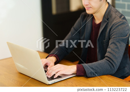 Male nomad worker using a computer in a cafe 113223722