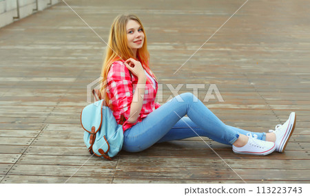 Happy caucasian teenager girl with backpack posing on city street 113223743