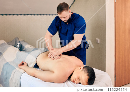 Treatment of back pain with physiotherapy, man lies on massage table while being massaged. Treatment of back pain with physiotherapy, man lies on massage table while being massaged. 113224354