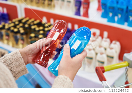 Woman buyer chooses shampoo in store Woman buyer chooses shampoo in store 113224422