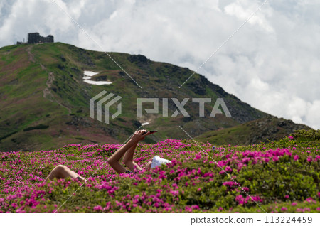 A boy with a white panama on his head sits between rhododendrons with a view of Pip Ivan. 113224459