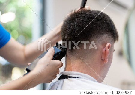 Professional hairdresser working with client. Hair salon master trimmed client hair with electric razor at barber shop. Professional hairdresser working with client. Hair salon master trimmed client hair with electric razor at barber shop. 113224987