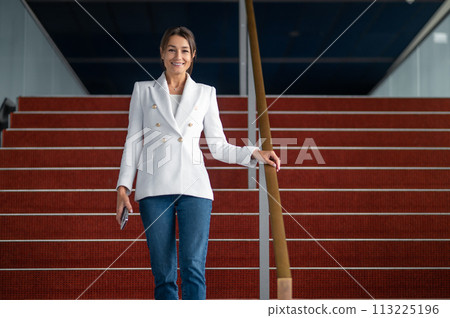 Woman in white jacket near the red stairs in the office building 113225196