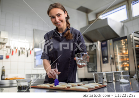 Woman baker baking croissant in bakehouse 113225252