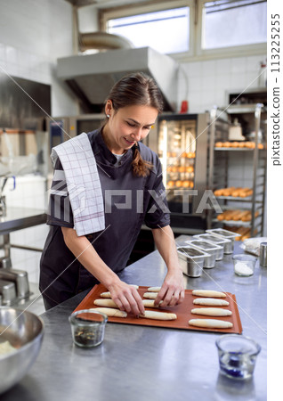 Woman baker baking croissant in bakehouse 113225255