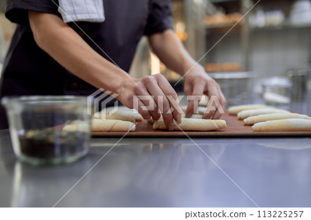 Unrecognizable woman baker baking croissant in bakehouse 113225257