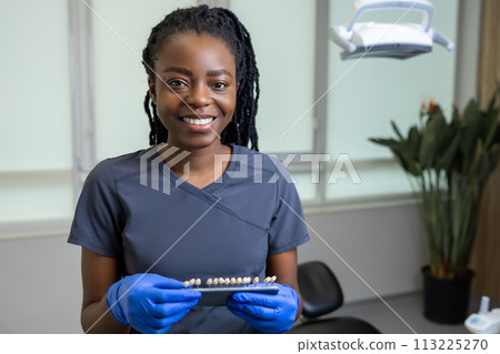 Woman dentist holding dental teeth shade guide chart 113225270