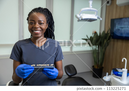 Female dentist holding dental teeth shade guide chart 113225271