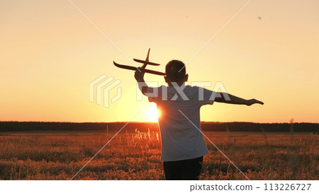 boy runs with plane his hand, child boy plays with toy plane, child son runs happily through field sunset, fantastic dream airplane pilot, cheerful child boy runs happily with toy plane through park 113226727