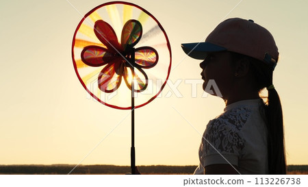 toy windmill sunset, child girl looking sunset holding windmill hand, catching wind glare sunset, glare sunset toy windmill, child silhouette with windmill her hand, child girl daughter dream, family 113226738