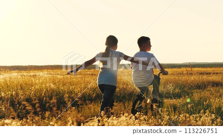 happy girl runs catching up with boy, child boy rides bicycle, son pedals, girl daughter plays airplane pilot, childhood dream airplane pilot fly, running sunset park, happy family kid, spinning wheel happy girl runs catching up with boy, child boy rides bicycle, son pedals, girl daughter plays airplane pilot, childhood dream airplane pilot fly, running sunset park, happy family kid, spinning wheel 113226751