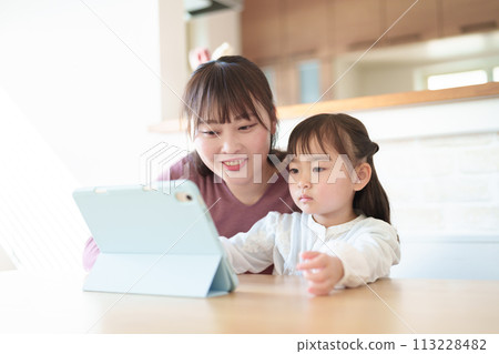 Parent and child using a tablet in the living room 113228482