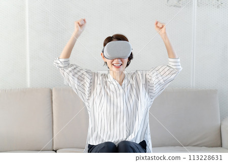 A woman enjoying herself while wearing VR goggles 113228631