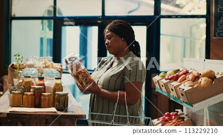 Client looks for organic natural food items in zero waste store, looking for chemicals free pasta or grains in glass jars. African american buyer supporting sustainable lifestyle and local farming. Client looks for organic natural food items in zero waste store, looking for chemicals free pasta or grains in glass jars. African american buyer supporting sustainable lifestyle and local farming. 113229210