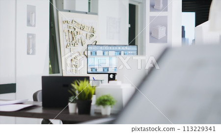 Empty architectural office filled with manufacturing tools and design elements, coworking space for unicorn business. 3d building models, blueprints and graphic software accessories. 113229341
