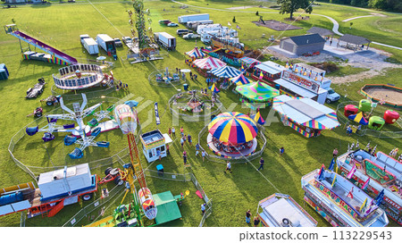 Aerial View of Bustling Carnival with Ferris Wheel and Rides at Golden Hour 113229543