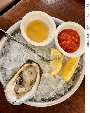Fresh Oyster on Ice with Sauces and Lemon Wedges Overhead View 113229753