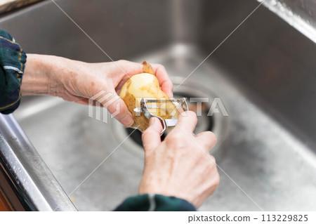Peeling potatoes with a peeler Peeling potatoes with a peeler 113229825