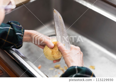 Peeling potatoes with a peeler 113229930