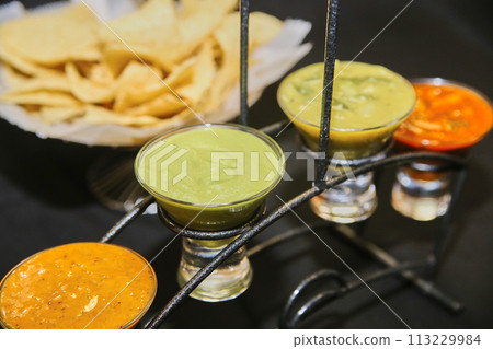 Trio of Mexican Salsas with Tortilla Chips on Wrought Iron Stand 113229984