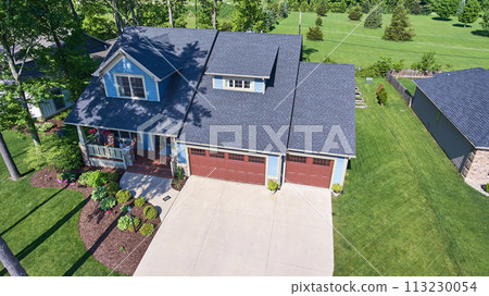 Aerial View of Blue Suburban Home with Red Garage Doors in Serene Neighborhood Aerial View of Blue Suburban Home with Red Garage Doors in Serene Neighborhood 113230054