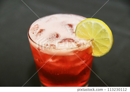 Vibrant Red Beverage with Lemon Garnish in Glass - Close-Up Perspective 113230112