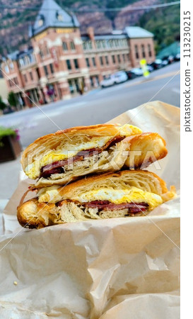 Croissant Breakfast Sandwich with Bacon in Urban Setting Croissant Breakfast Sandwich with Bacon in Urban Setting 113230215