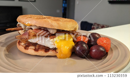 Hearty Breakfast Sandwich with Fresh Fruit Side on Beige Plate Hearty Breakfast Sandwich with Fresh Fruit Side on Beige Plate 113230359