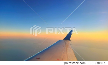 Aerial View of Airplane Wing at Sunrise, High Altitude Flight Perspective 113230414