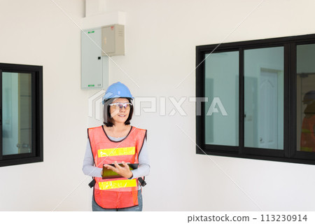 Asian women home Inspector surveyor wearing vests and hard hat at new property 113230914