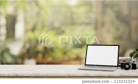 A laptop computer mockup on a white tabletop with a blurred background of a green garden. A laptop computer mockup on a white tabletop with a blurred background of a green garden. 113231324