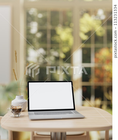 A laptop computer mockup and a coffee cup are placed on a wooden table in a beautiful coffee shop. 113231334