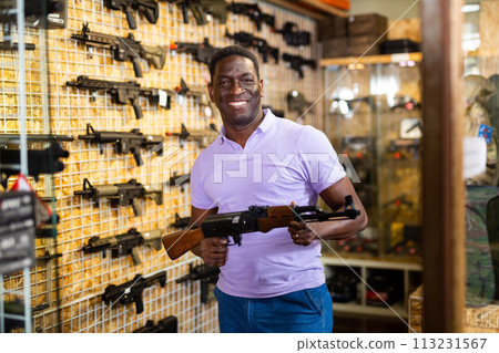 Positive man with assault rifle in airsoft shop Positive man with assault rifle in airsoft shop 113231567