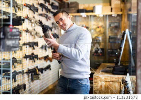 Man choosing assault rifle in arms shop 113231578