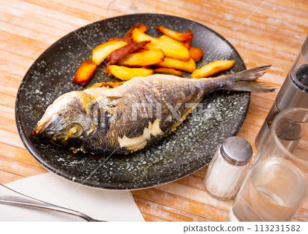 Roasted dorada served on plate with baked potatoes 113231582