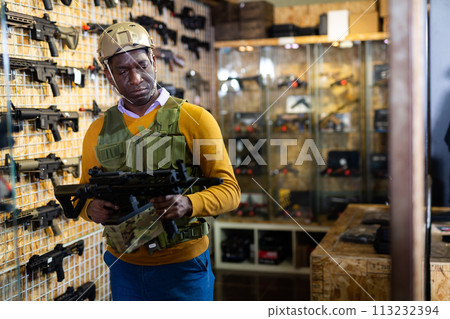 African american man in army uniform with weapon in military shop African american man in army uniform with weapon in military shop 113232394