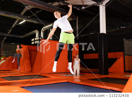 Emotional man jumping vertical and flying in trampoline sport center indoors 113232438