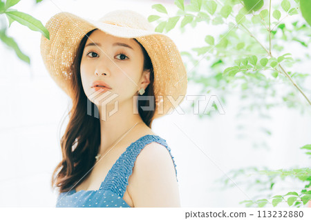 Young woman putting on a straw hat 113232880